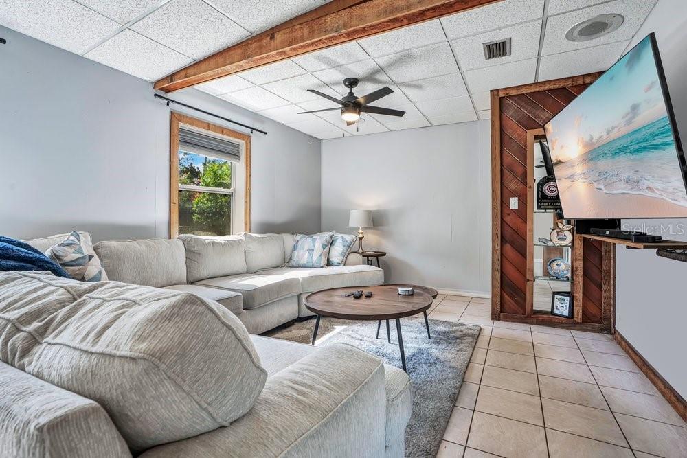 A living room features a sectional sofa, a coffee table, and a wall-mounted television — 310 E 6TH STREET, CHULUOTA, FL