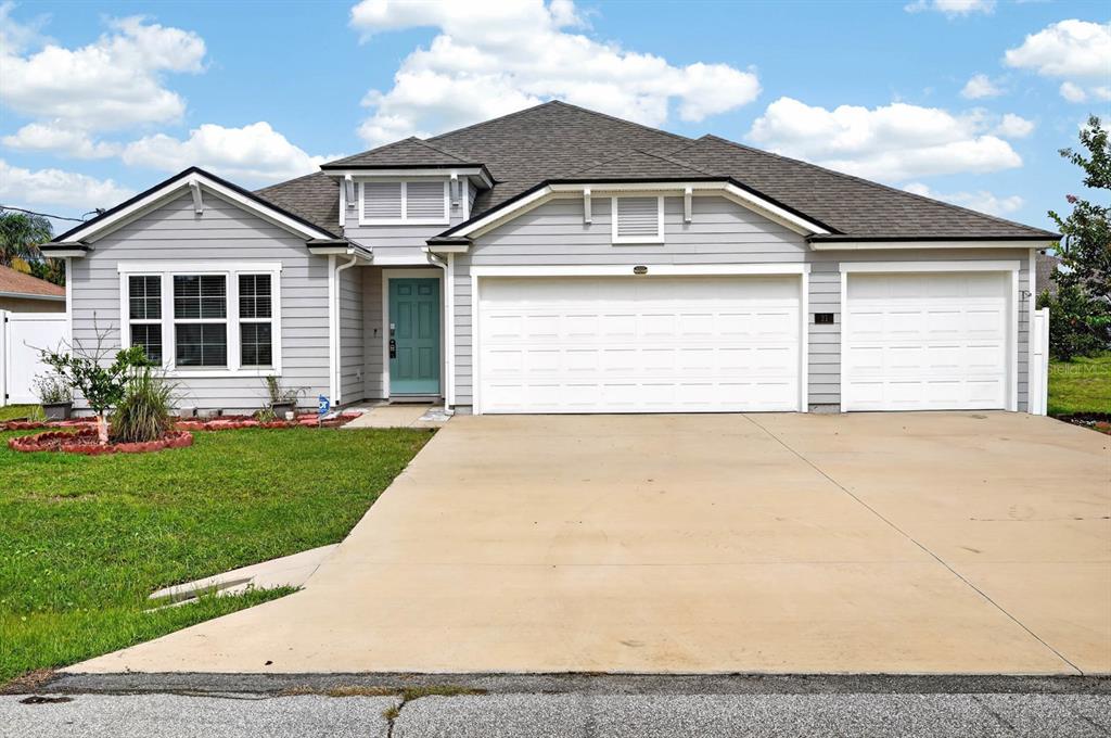 A single-story house with light gray siding, a three-car garage, and a teal front door — 21 ROCKING LANE, PALM COAST, FL