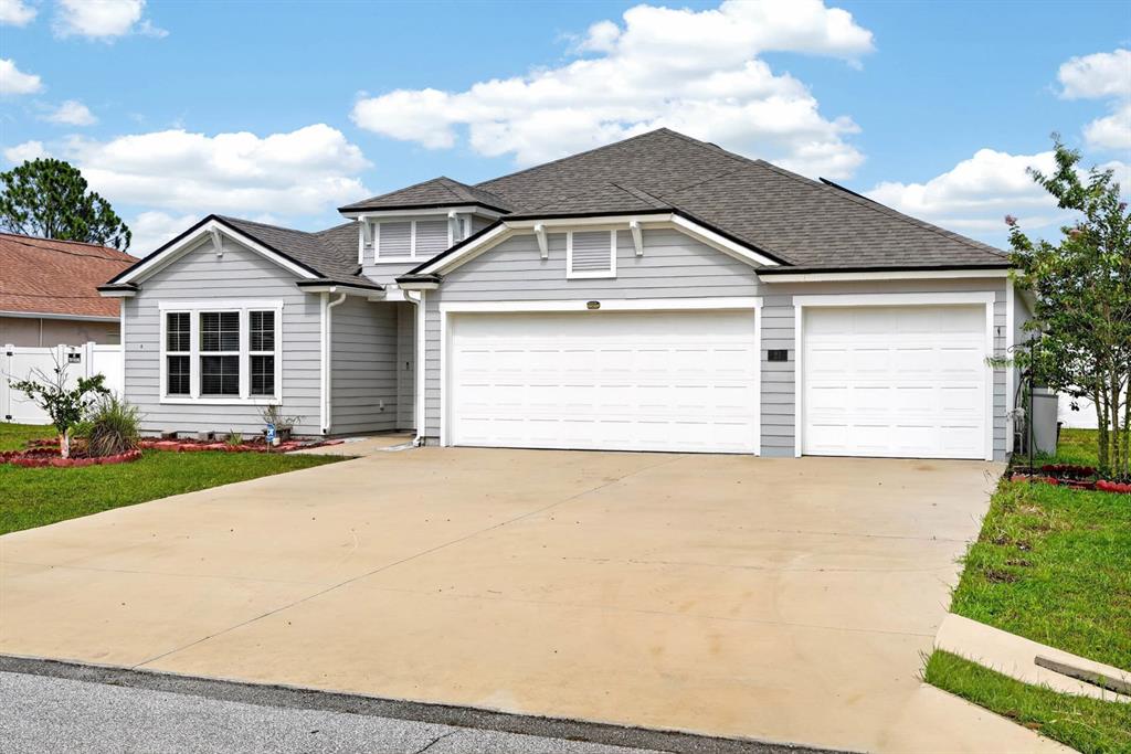 A light gray, single-story suburban house with a three-car garage and a concrete driveway — 21 ROCKING LANE, PALM COAST, FL