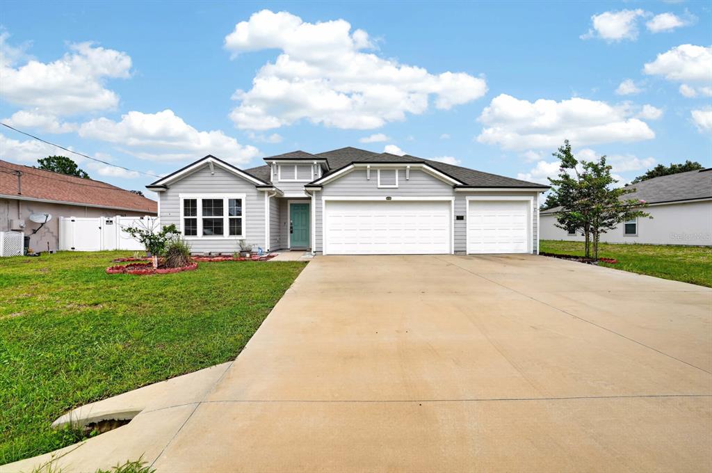 A single-story house with gray siding, a three-car garage, and a concrete driveway — 21 ROCKING LANE, PALM COAST, FL