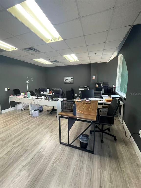 An office space features gray walls, light wood-look flooring, and several desks with computer equipment — 7075 KINGSPOINTE PARKWAY UNIT 9, ORLANDO, FL