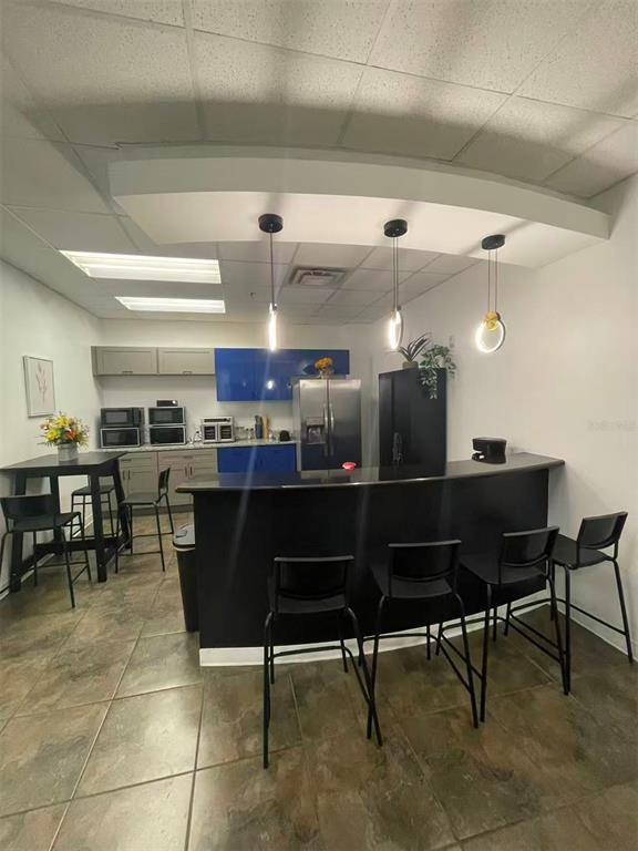 A kitchen area features a black curved bar, modern pendant lighting, and blue cabinetry — 7075 KINGSPOINTE PARKWAY UNIT 9, ORLANDO, FL