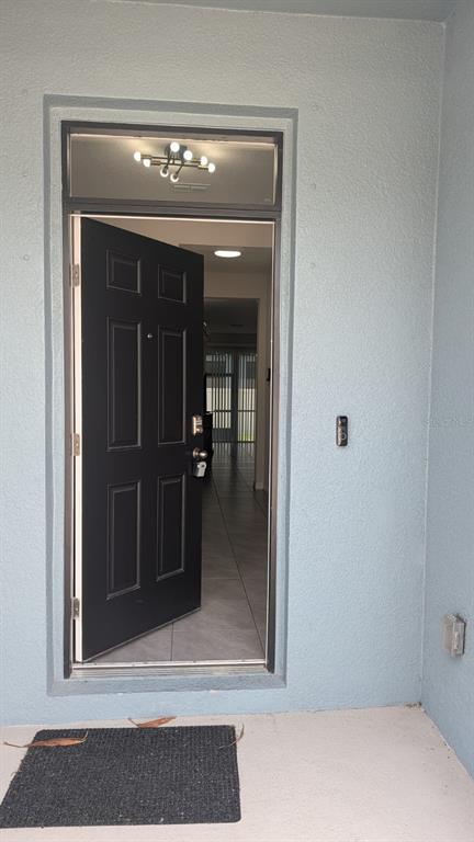 A black front door stands slightly open, revealing a tiled interior entryway and a ceiling light — 4015 BLUE BANKS LANE, BRADENTON, FL
