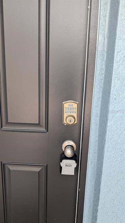 A dark-colored front door features a digital keypad deadbolt and a key lockbox — 4015 BLUE BANKS LANE, BRADENTON, FL