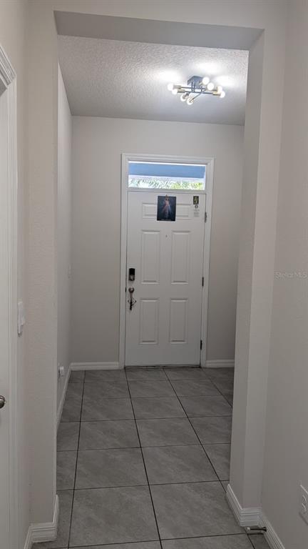 A tiled entryway features a white front door with a transom window and a modern light — 4015 BLUE BANKS LANE, BRADENTON, FL