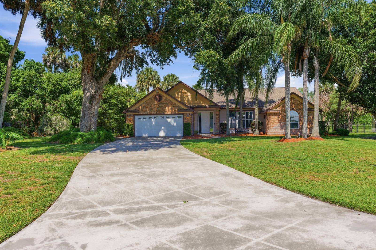 A single-story brick house with a white garage door and palm trees in the yard — 1960 SE 9th Avenue, Okeechobee FL 34974, OKEECHOBEE, FL