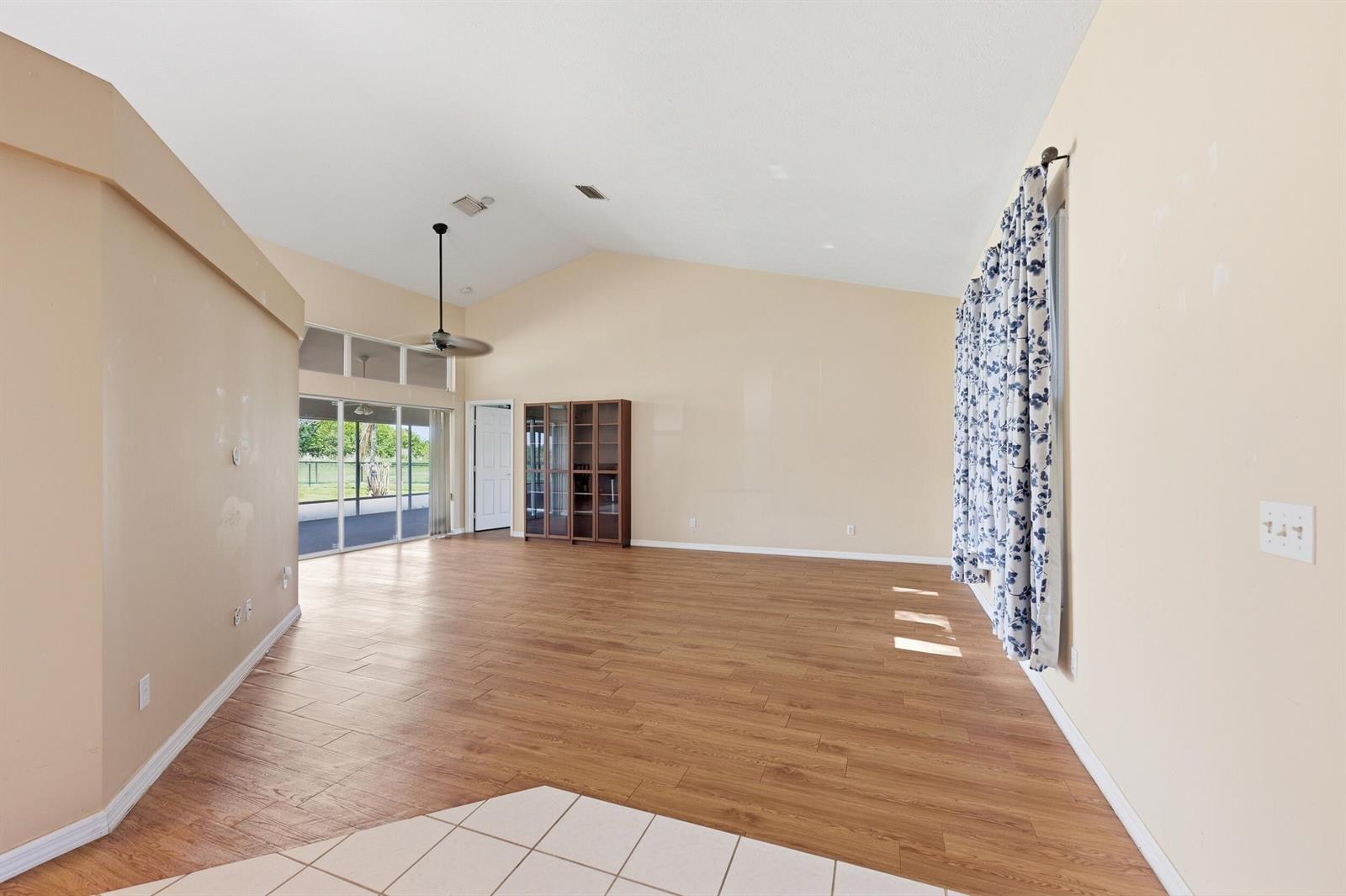 A spacious living room features vaulted ceilings, wood-look flooring, and a large sliding glass door — 1960 SE 9th Avenue, Okeechobee FL 34974, OKEECHOBEE, FL