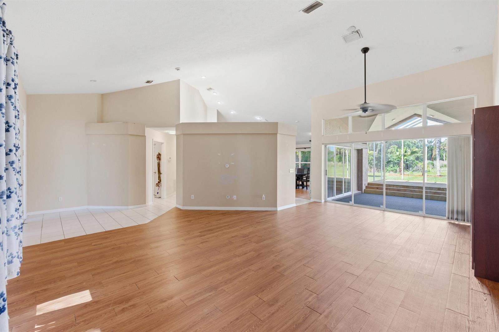 A spacious living room with wood-look flooring, vaulted ceilings, and large sliding glass doors — 1960 SE 9th Avenue, Okeechobee FL 34974, OKEECHOBEE, FL