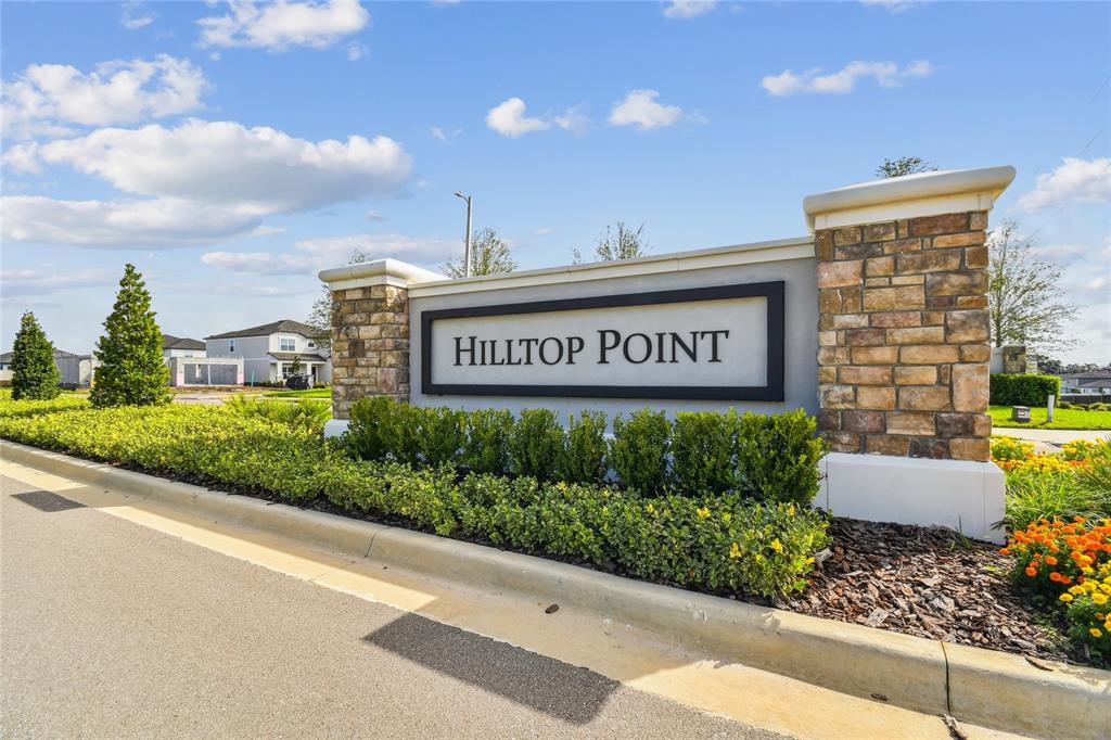 A stone and stucco monument sign for Hilltop Point stands beside a paved road — 11810 PHILLIPOS STREET, DADE CITY, FL