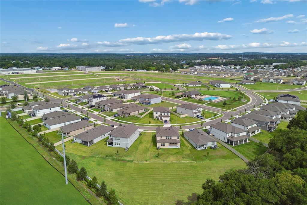 An aerial view shows a suburban neighborhood with single-family homes, a community pool, and lawns — 11810 PHILLIPOS STREET, DADE CITY, FL
