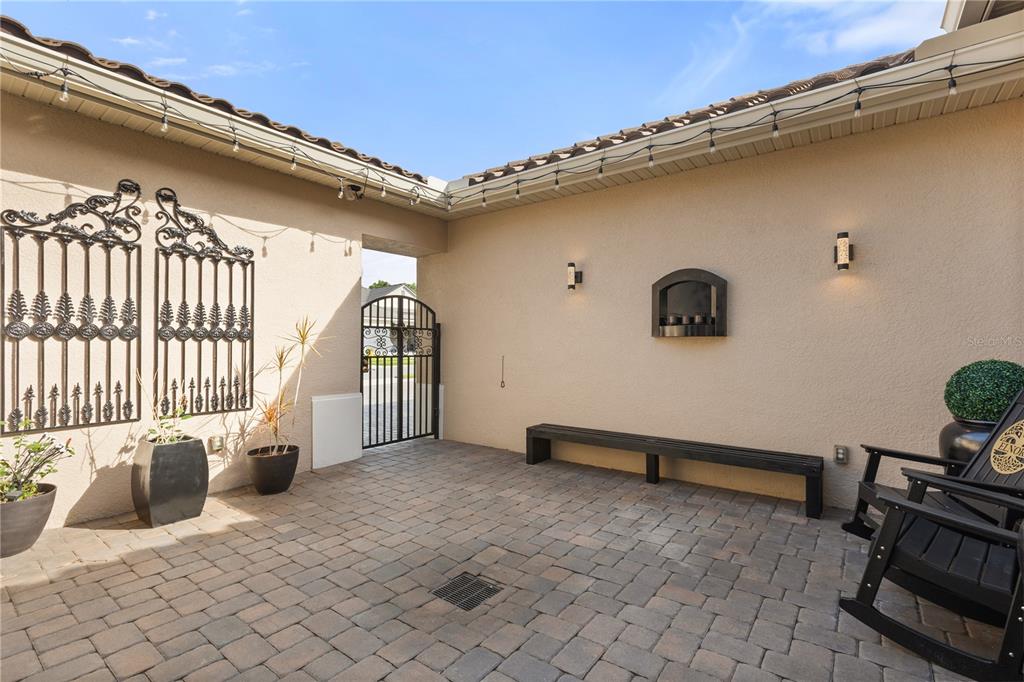 A paved courtyard features a black metal gate, a long bench, and decorative wall sconces — 3880 GRASSLAND LOOP, LAKE MARY, FL