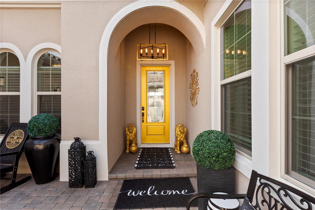 A bright yellow front door is framed by an arched entryway with two lion statues — 3880 GRASSLAND LOOP, LAKE MARY, FL