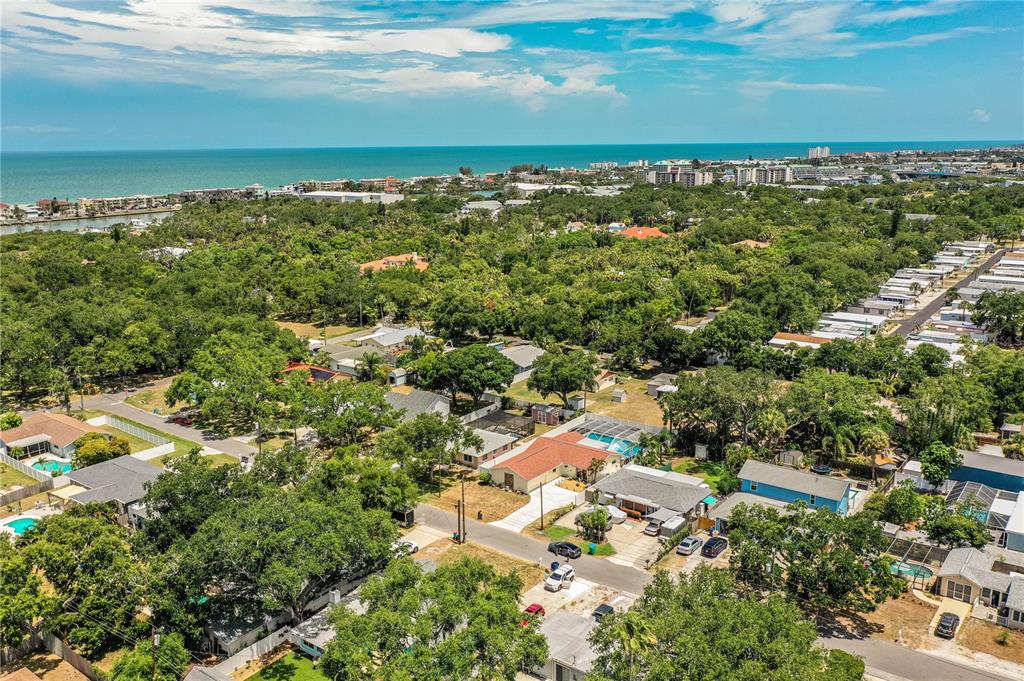 An aerial view shows a residential neighborhood with houses, swimming pools, and dense trees — 14803 SUNSET DRIVE, LARGO, FL