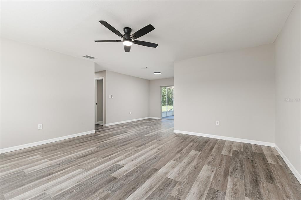 An open living area features light gray walls, wood-look flooring, and a black ceiling fan — 4994 E HINSON AVENUE, HAINES CITY, FL