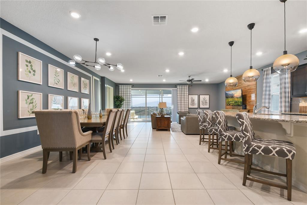 An open-concept living and dining area features tile floors, a kitchen island, and blue walls — 2060 LELANI CIR, DAVENPORT, FL