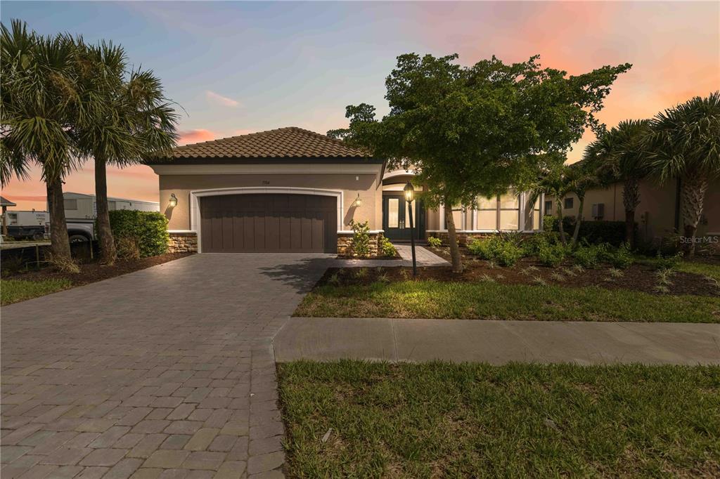 A single-story house with a tile roof, a two-car garage, and landscaped front yard — 7704 MOONBEAM AVENUE, SARASOTA, FL