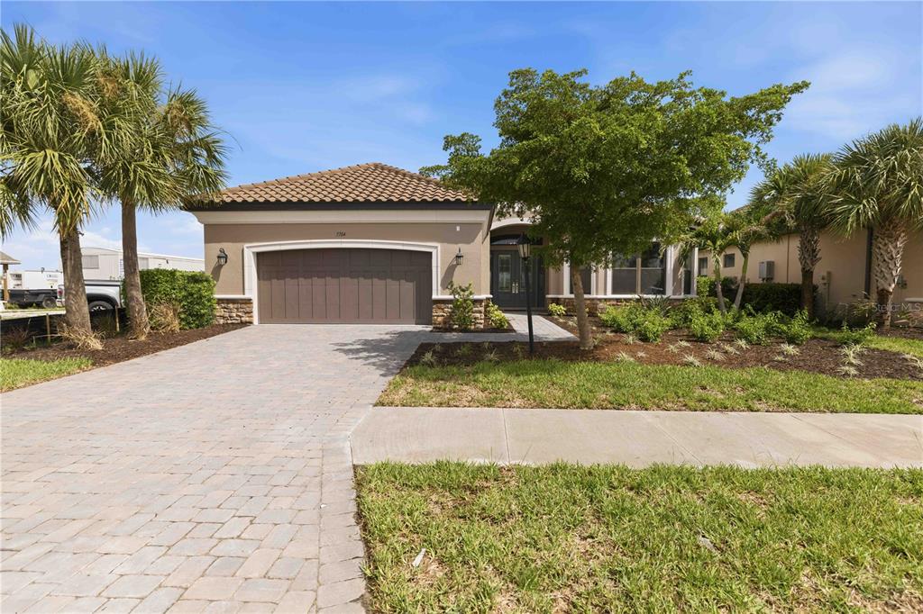 A single-story house with a paved driveway, two-car garage, and a tiled roof — 7704 MOONBEAM AVENUE, SARASOTA, FL