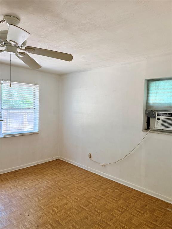 An empty room features wood parquet flooring, a ceiling fan, and a window air conditioner — 7055 MERRICK LANE, SPRING HILL, FL