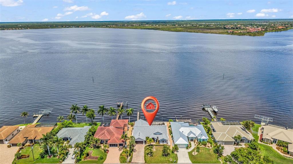 An aerial view shows a waterfront house with a red location pin on a lake — 12558 BACCHUS ROAD, PORT CHARLOTTE, FL