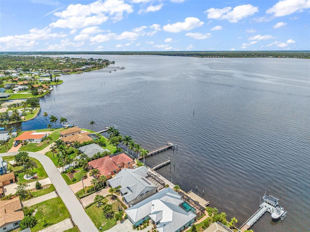 An aerial view shows waterfront houses with private docks along a large lake — 12558 BACCHUS ROAD, PORT CHARLOTTE, FL