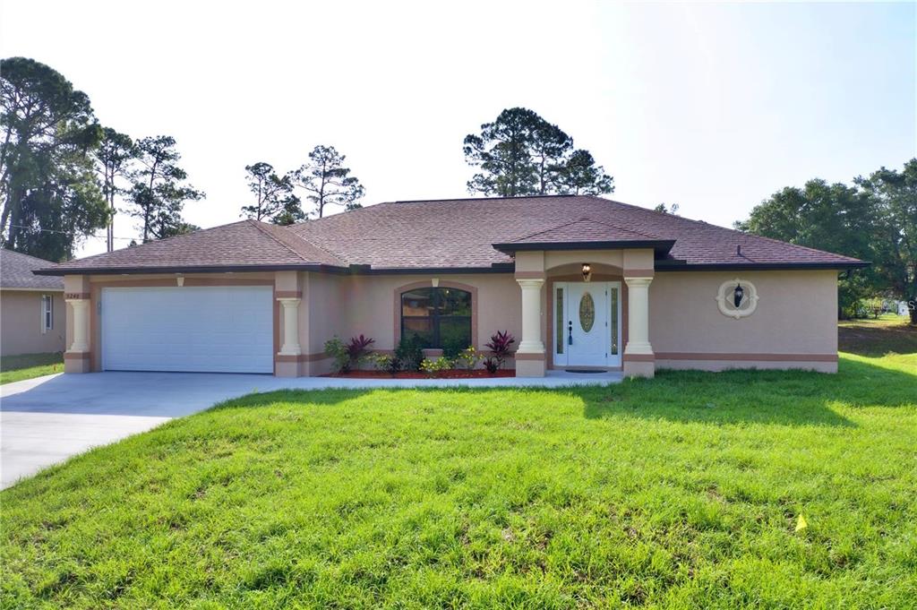 A single-story house with a tan stucco exterior, a two-car garage, and a covered entryway — 4851 KENNETT STREET, NORTH PORT, FL