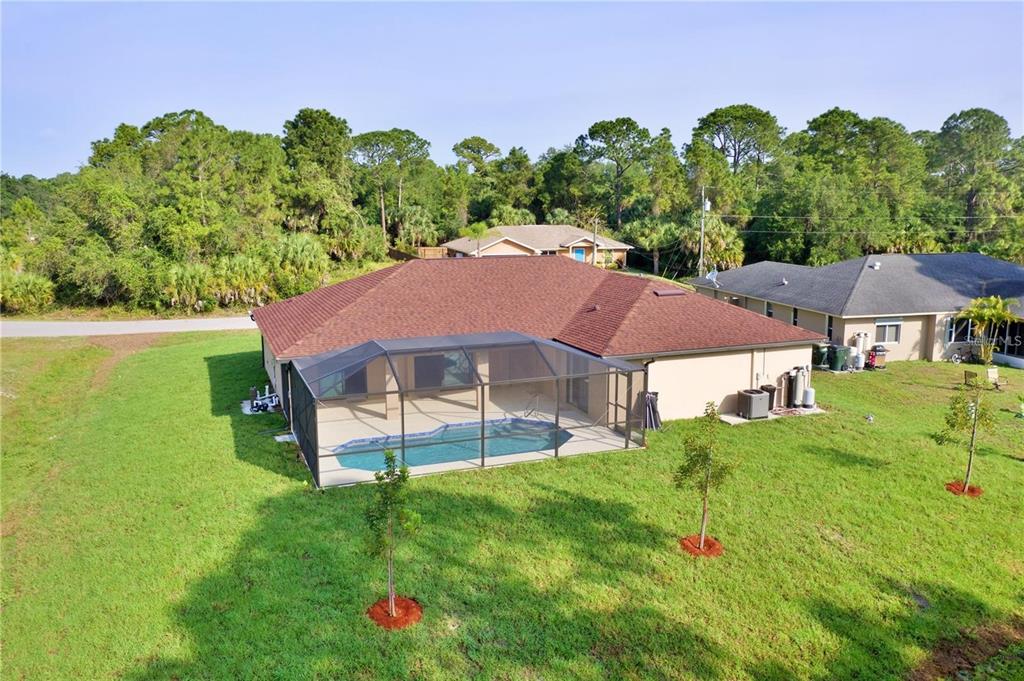An aerial view of a house with a screened-in pool and a large grassy backyard — 4851 KENNETT STREET, NORTH PORT, FL