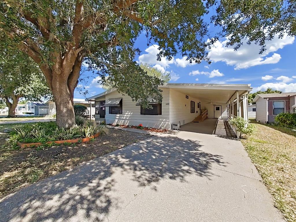 A single-story house with a carport, a large tree, and a concrete driveway — 1688 FOXWAY DR, LAKELAND, FL