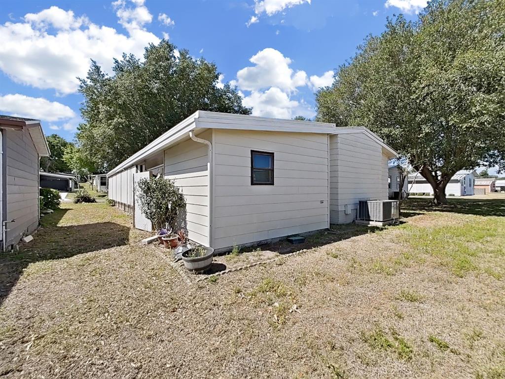 The exterior of a light-colored mobile home features horizontal siding and a single window — 1688 FOXWAY DR, LAKELAND, FL