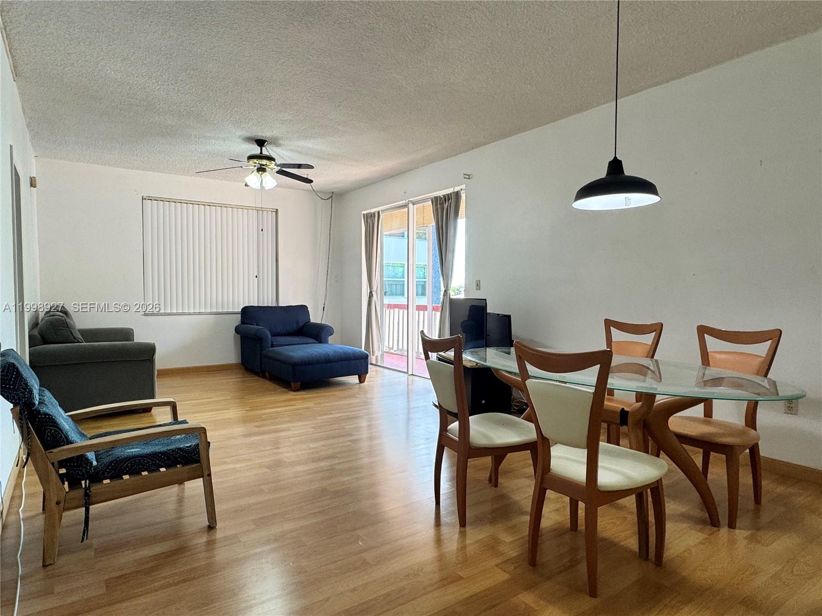 A living and dining area features wood flooring, a ceiling fan, and a glass-topped table — 18707 NE 14th Ave # 733, Miami FL 33179, MIAMI, FL