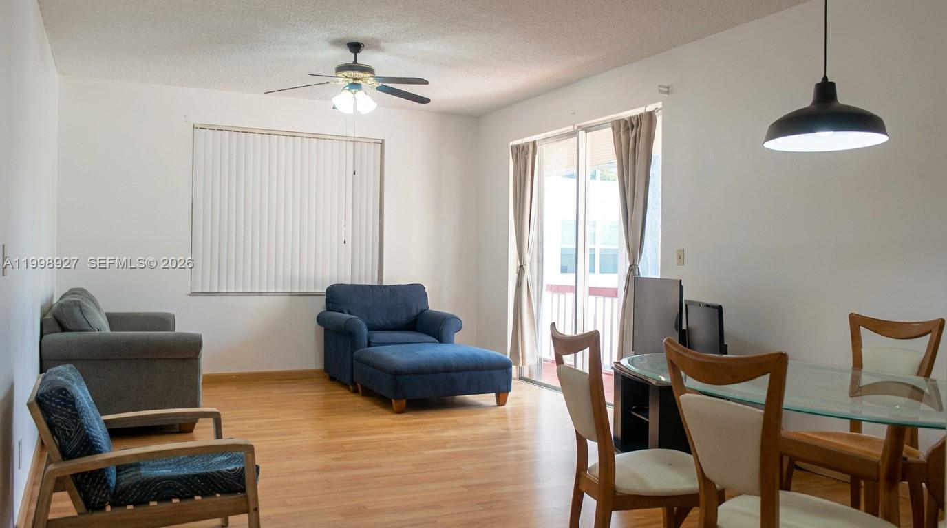 A living and dining area features wood flooring, a ceiling fan, and a sliding glass door — 18707 NE 14th Ave # 733, Miami FL 33179, MIAMI, FL