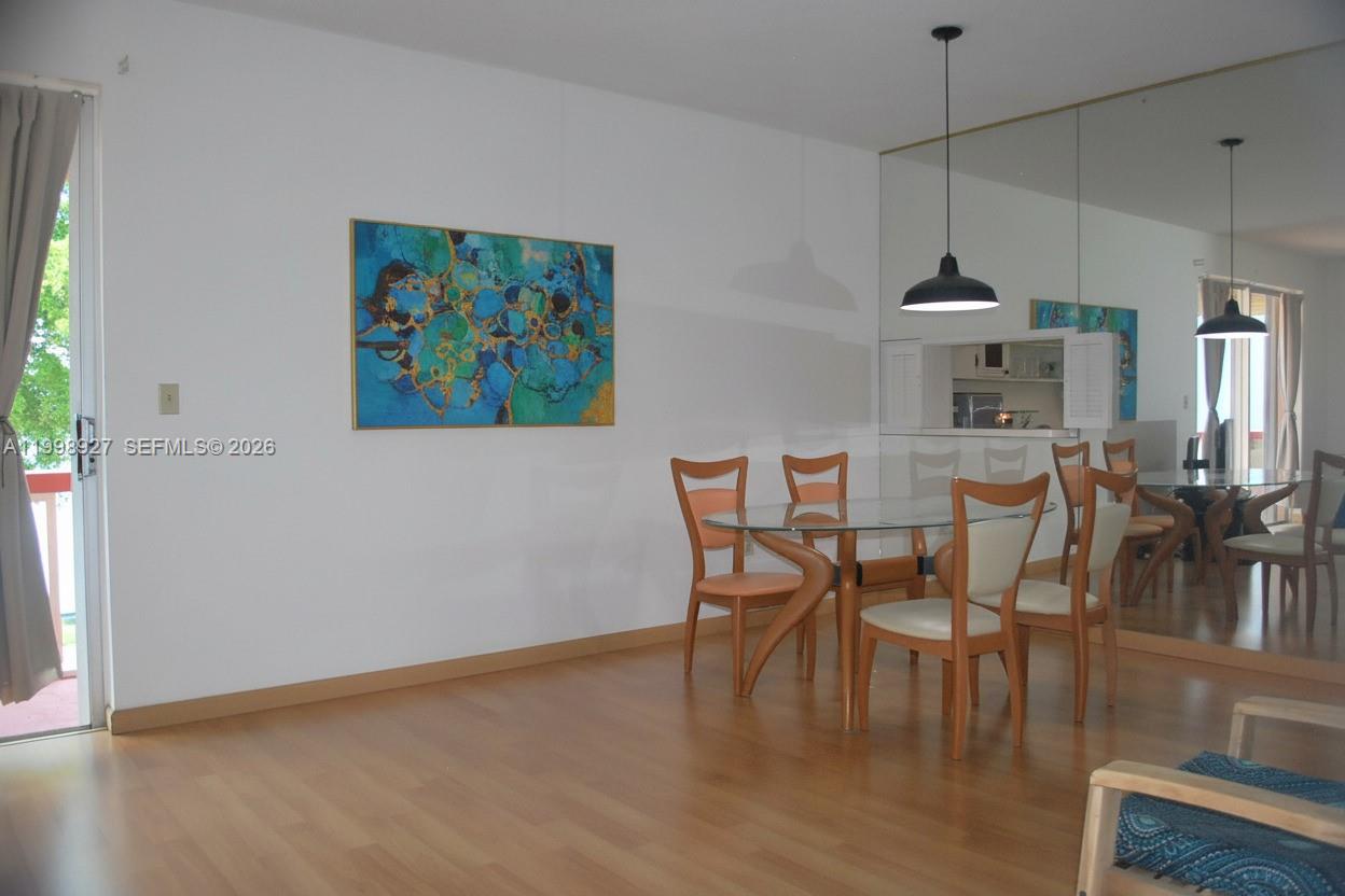 A dining area features a glass table, wooden chairs, pendant lighting, and a mirrored wall — 18707 NE 14th Ave # 733, Miami FL 33179, MIAMI, FL