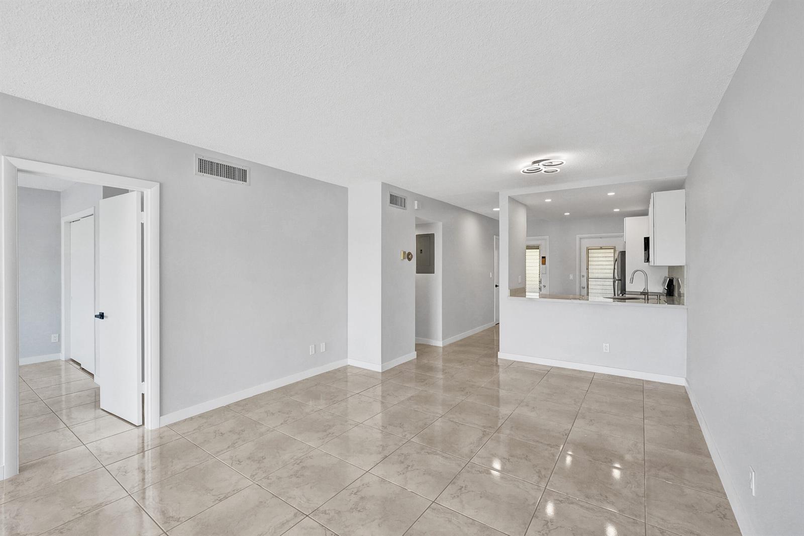An open-concept living area with light gray walls and large, glossy beige floor tiles — 455 Paradise Isle Boulevard # 305, Hallandale Beach FL 33009, HALLANDALE BEACH, FL