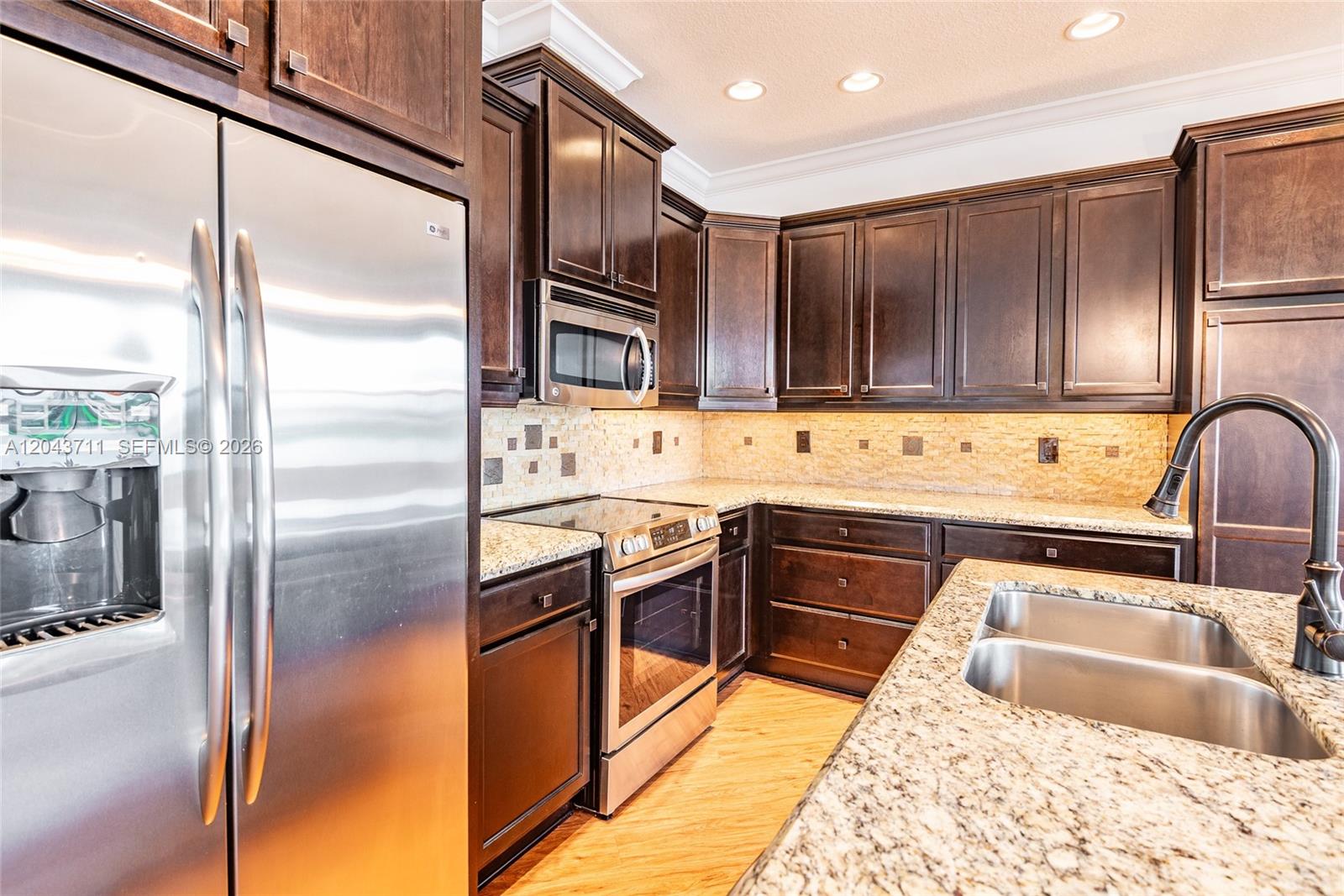 A kitchen features dark wood cabinets, stainless steel appliances, and granite countertops — 3061 Tortola Way, Cooper City FL 33024, COOPER CITY, FL