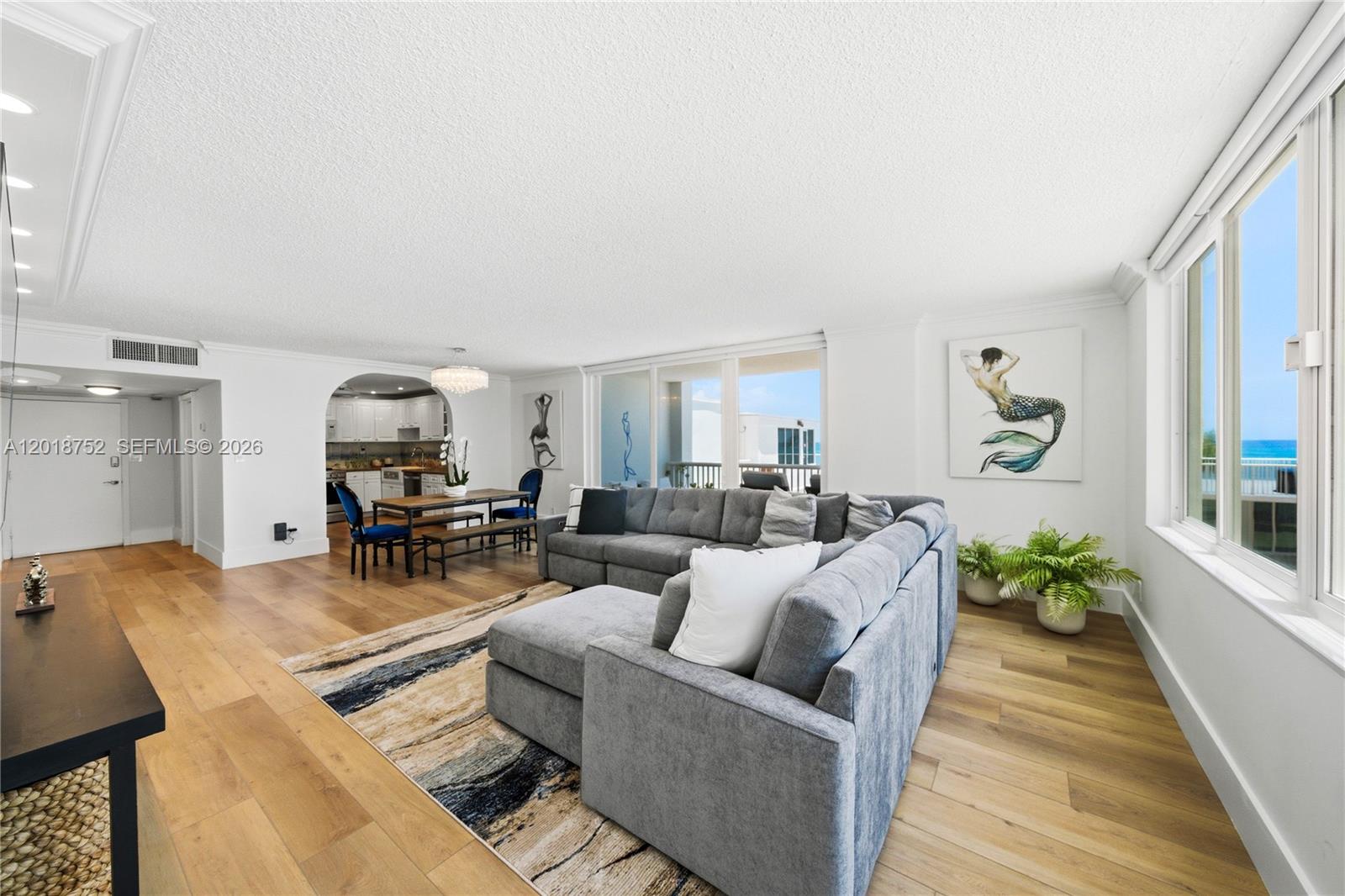 A living room with a gray sectional sofa, wood flooring, and a view of the ocean — 5401 Collins Ave # 102, Miami Beach FL 33140, MIAMI BEACH, FL