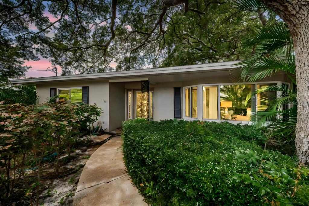A single-story house with a concrete walkway, large bay window, and mature trees overhead — 1704 CYPRESS AVENUE, BELLEAIR, FL