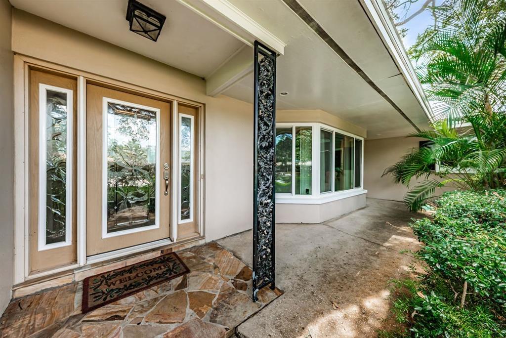 A front entrance features a wood door with glass panels, a stone porch, and landscaping — 1704 CYPRESS AVENUE, BELLEAIR, FL