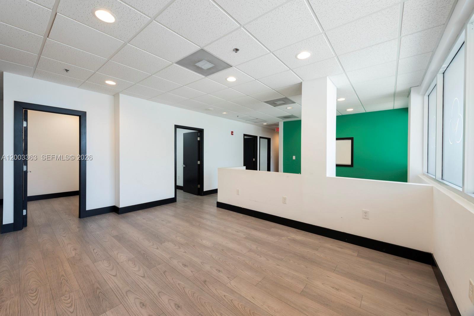 An office space features white walls, black door frames, light wood flooring, and a green accent wall — 6141 Sunset Dr # 110, South Miami FL 33143, SOUTH MIAMI, FL