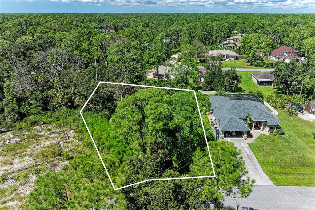 An aerial view shows a wooded, undeveloped lot outlined in white next to a house — Lot 28 ZINKLE STREET, NORTH PORT, FL