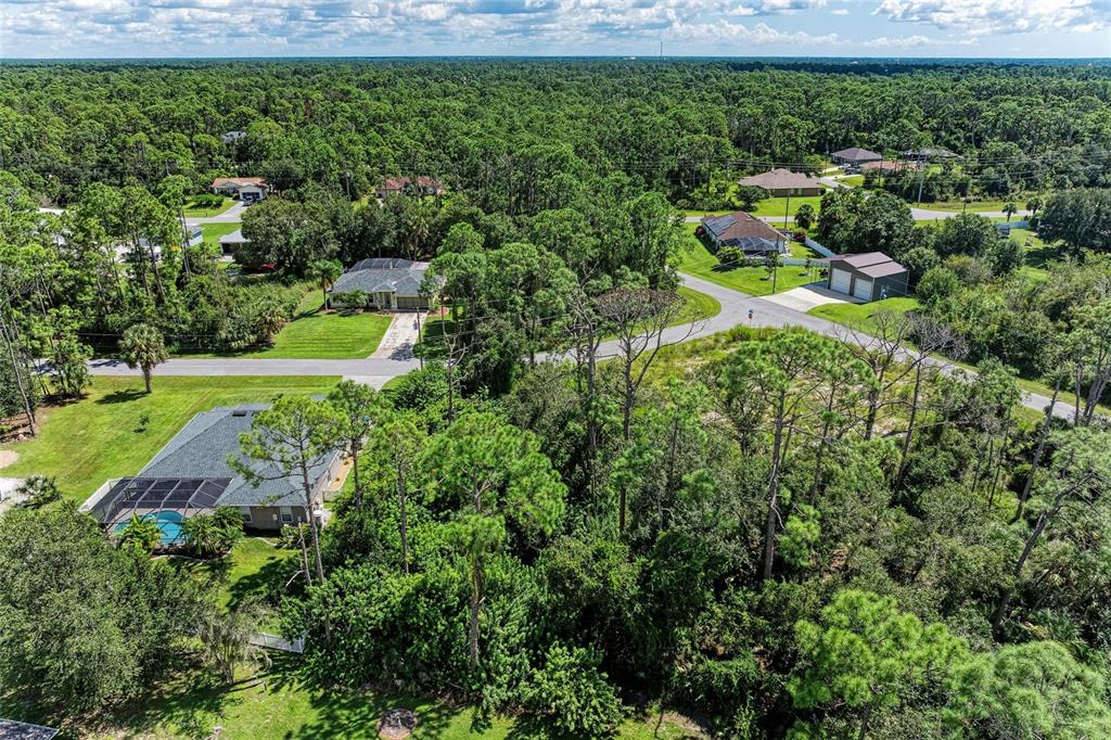 An aerial view shows several houses surrounded by dense trees and a paved road — Lot 28 ZINKLE STREET, NORTH PORT, FL