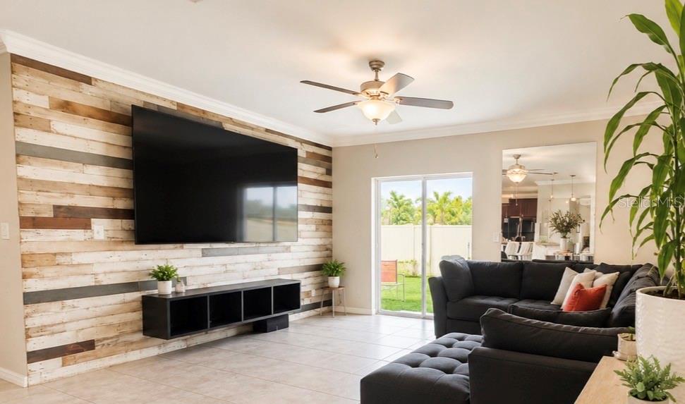 A living room features a wood-paneled accent wall, a large television, and a dark sectional — 17204 YELLOW PINE STREET, WIMAUMA, FL