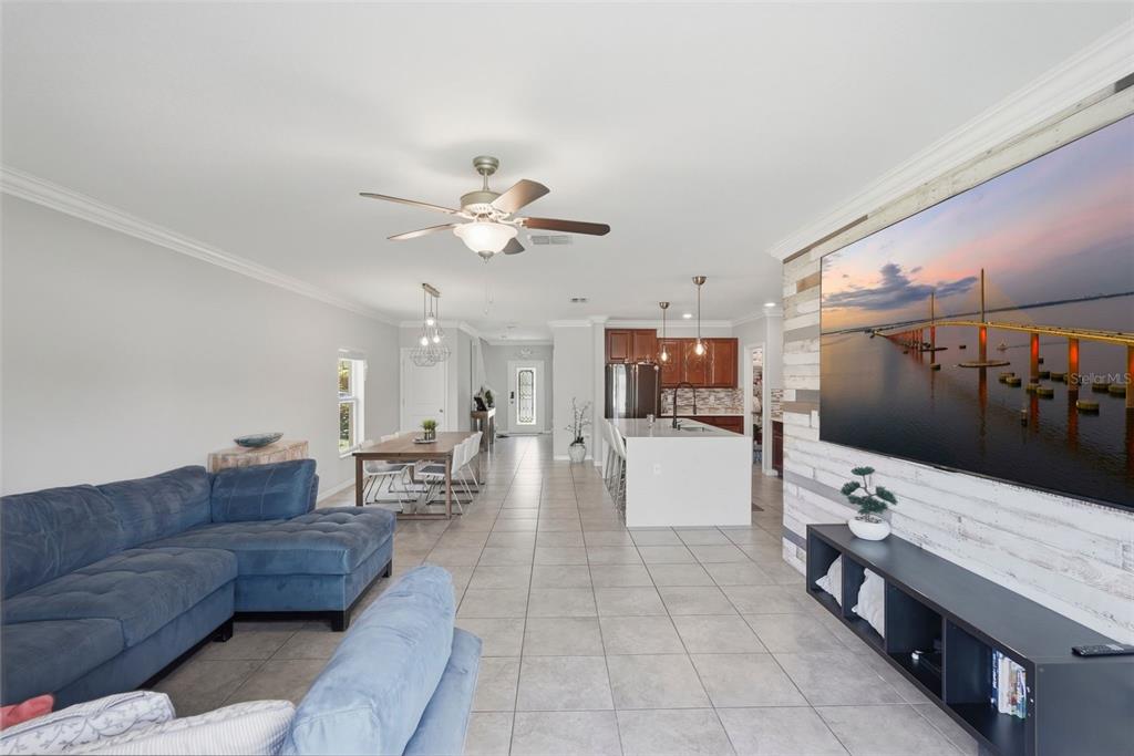 An open-concept living room and kitchen featuring tile floors, a blue sectional, and a television — 17204 YELLOW PINE STREET, WIMAUMA, FL
