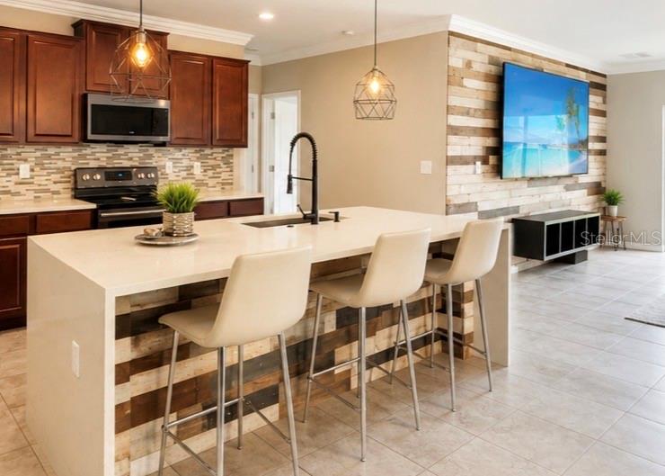 A kitchen features a quartz waterfall island, wood-paneled accents, and dark cabinetry — 17204 YELLOW PINE STREET, WIMAUMA, FL