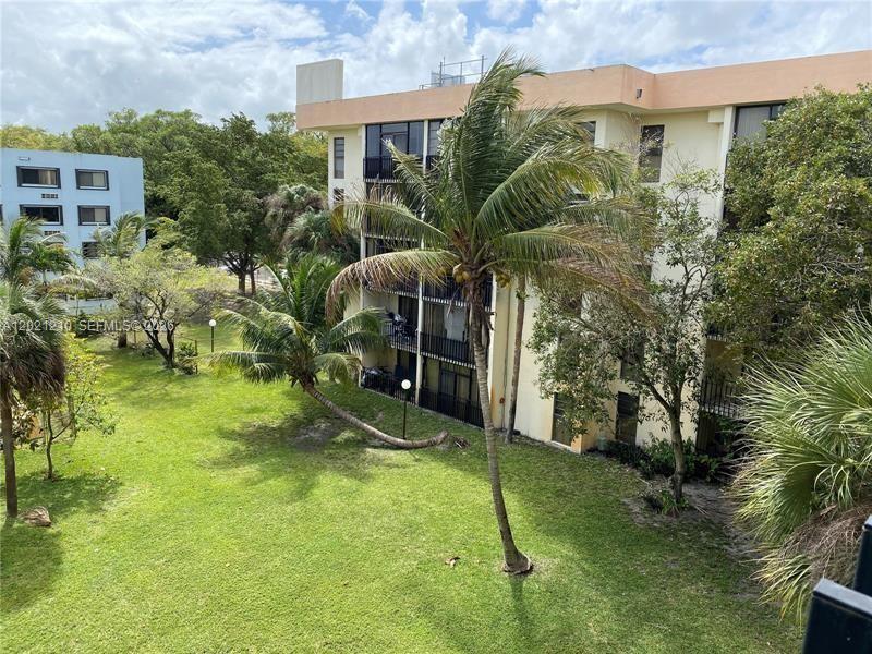 A multi-story apartment building overlooks a grassy courtyard with several palm trees — 650 NE 149th St # 407A, Miami FL 33161, MIAMI, FL