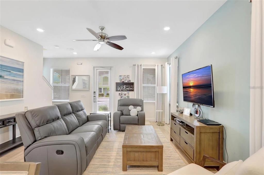 A living room features a gray sofa, a wooden coffee table, and a wall-mounted television — 8044 LOST SHAKER LANE, KISSIMMEE, FL