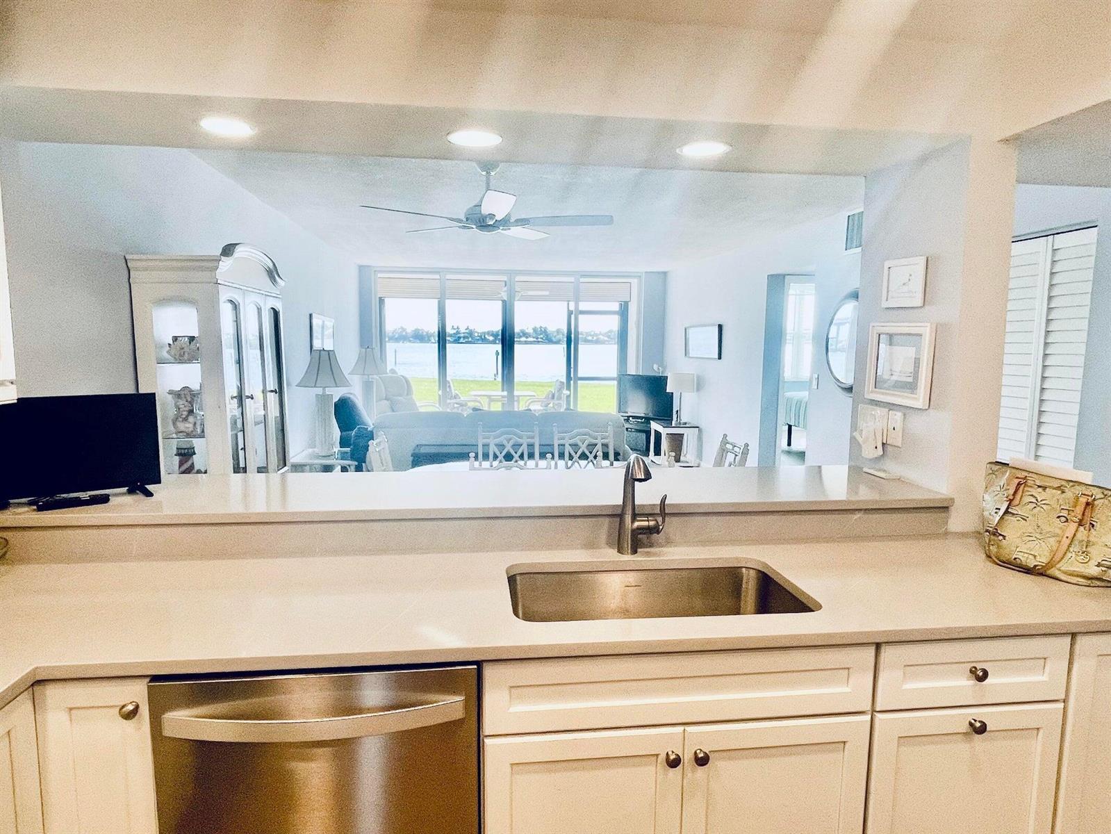 A kitchen sink and dishwasher overlook a living room with a view of the water — 1950 SW Palm City Road # 13104, Stuart FL 34994, STUART, FL
