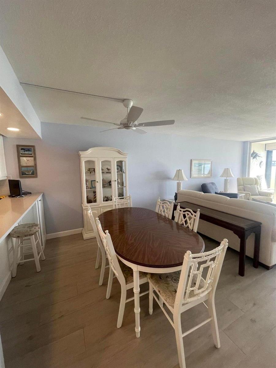 A dining area with a wooden table and chairs sits adjacent to a living room — 1950 SW Palm City Road # 13104, Stuart FL 34994, STUART, FL