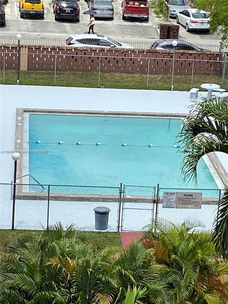 An outdoor swimming pool is enclosed by a chain-link fence with a parking lot nearby — 440 E 23rd St # 1305, Hialeah FL 33013, HIALEAH, FL
