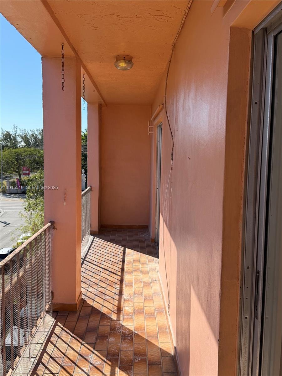 An outdoor balcony features tiled flooring, peach-colored walls, and a metal railing — 440 E 23rd St # 1305, Hialeah FL 33013, HIALEAH, FL