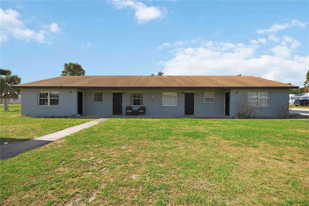 A single-story, gray multi-unit residential building with a brown roof and four black doors — 1118 MELODY LANE, SEBRING, FL