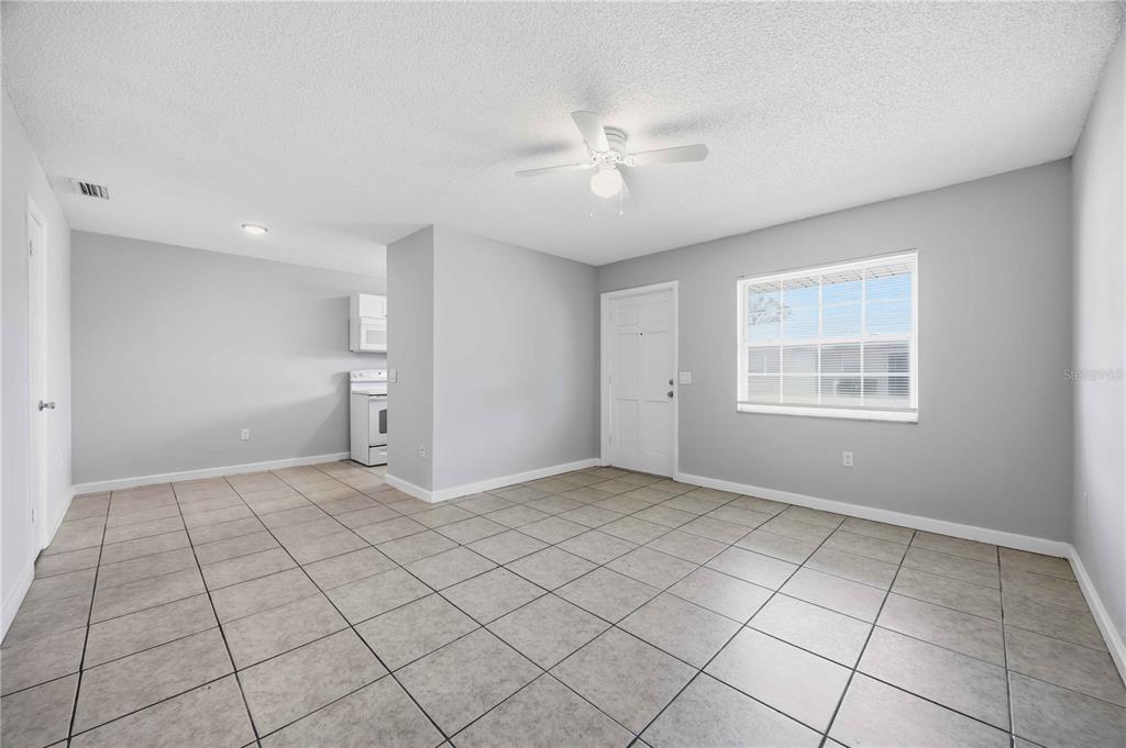 An empty room with light gray walls, tile flooring, a ceiling fan, and a window — 1118 MELODY LANE, SEBRING, FL